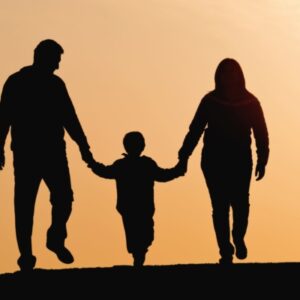 Silhuetter i solnedgangslys barnmed mor og far, set bagfra
